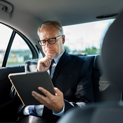 senior businessman with tablet pc driving in car